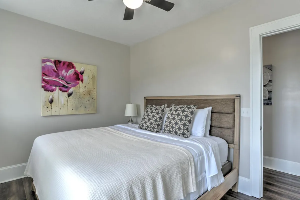 A serene bedroom with a comfortable bed, soft lighting from a bedside lamp, and calming artwork, all combining to create a restful ambiance. The gentle illumination suggests a soothing environment for unwinding after a day of wellness activities.
