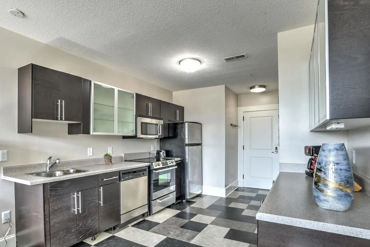 A modern kitchen featuring sleek appliances, ample countertop space, storage cabinets, and a decorative vase. The layout emphasizes functionality and aesthetic appeal, making it ideal for cooking and socializing.