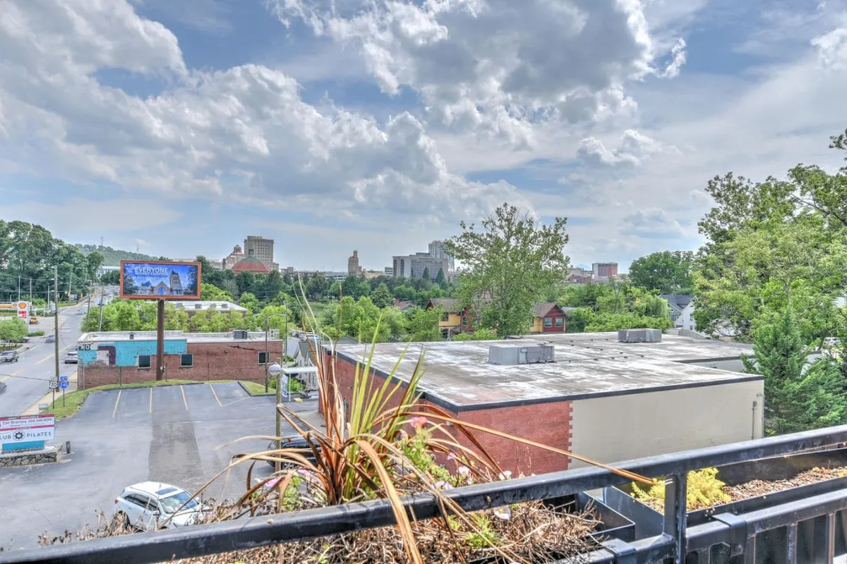 A panoramic view of the surrounding cityscape, complete with skyline, verdant foliage, and commercial buildings. The energetic mood is enhanced by visible local activities, hinting at the broader context of city life just steps away.